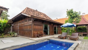 A traditional wooden building with a tiled roof, a swimming pool, and outdoor seating.