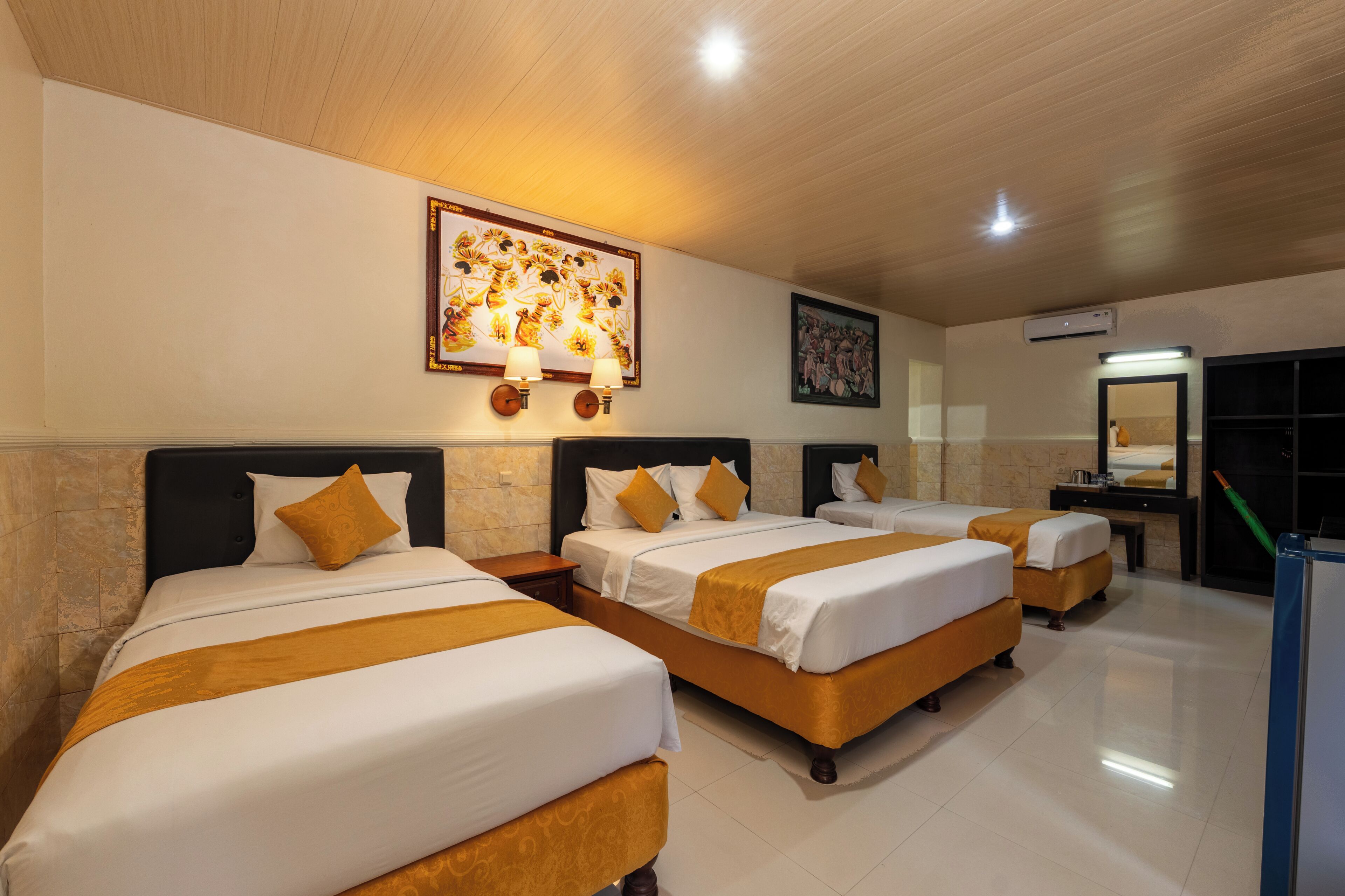 A hotel room with four beds, a large painting on the wall, and a ceiling fan.