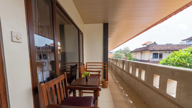 A balcony with a wooden table and chairs, a potted plant, and a view of a residential area.
