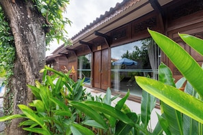 A traditional wooden building with large windows and a tree in the foreground.