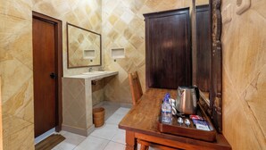 A bathroom with a wooden door, a sink, a mirror, and a wooden table with toiletries.