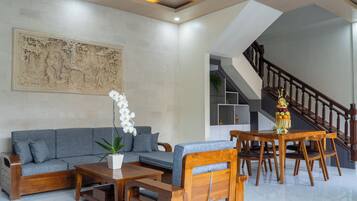 Un salon moderne avec un canapé gris, une table basse en bois et un escalier menant à un niveau supérieur.