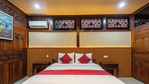 A hotel room with a large bed, wooden paneling, and a decorative wall panel.