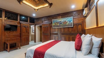 Une chambre d’hôtel avec un grand lit, des boiseries, un tableau et un téléviseur à écran plat.