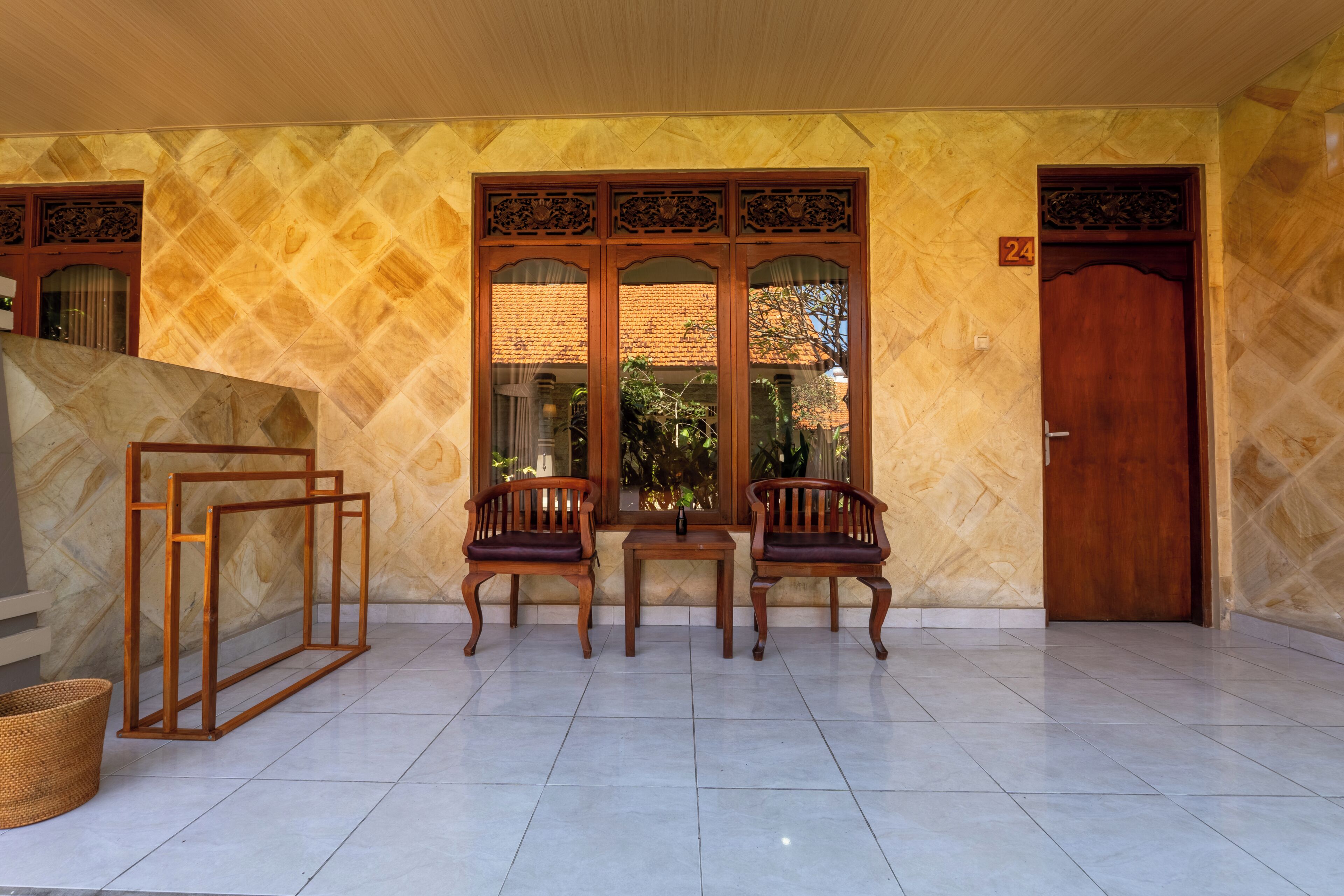 A room with a tiled floor, two wooden chairs, a small table, and a door marked with the number 24.