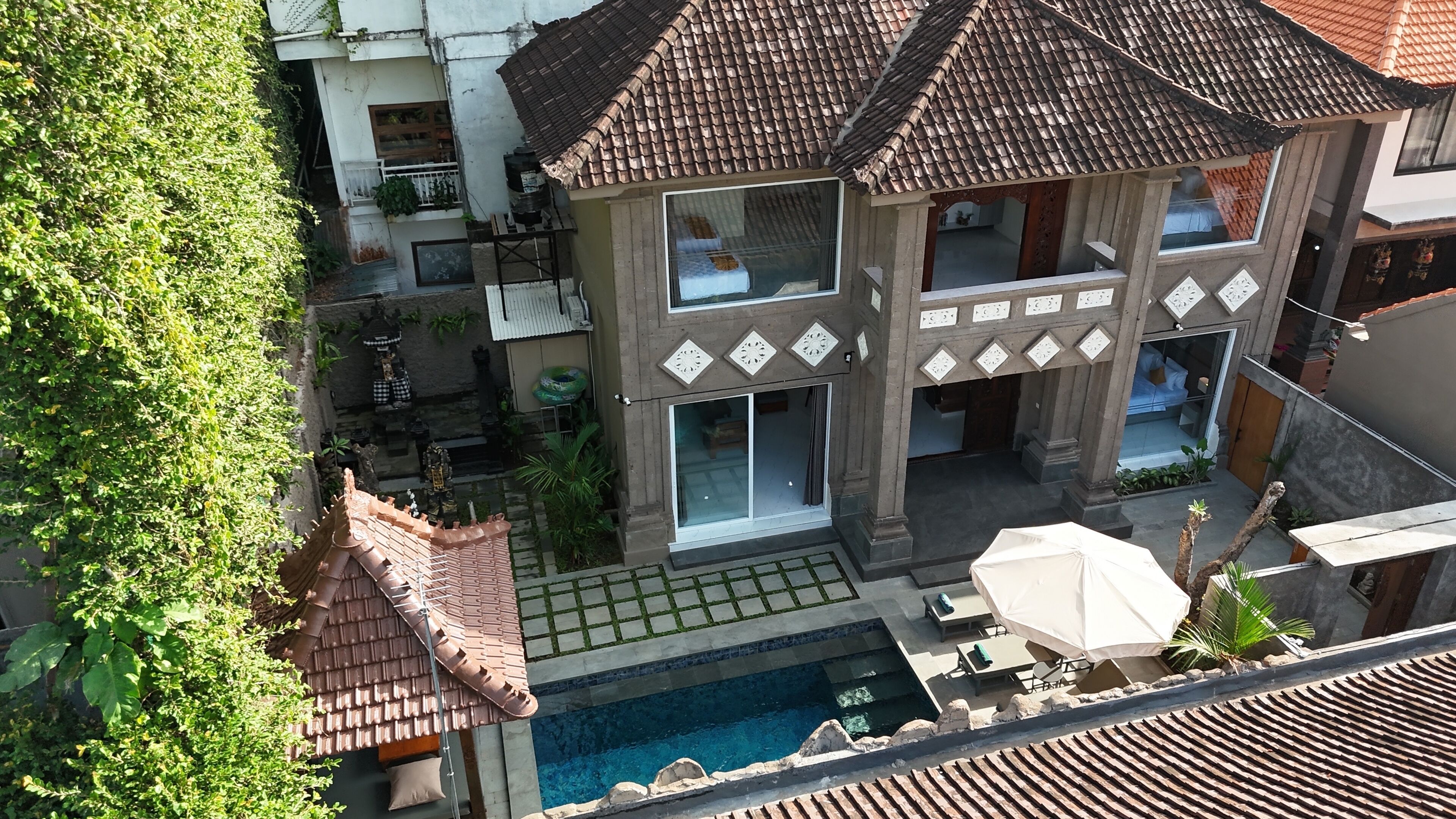 A two-story building with a swimming pool, outdoor seating, and a covered patio area.