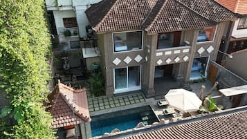 A two-story building with a swimming pool, outdoor seating, and a covered patio area.