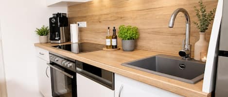 A modern kitchen with a stainless steel sink, a built-in oven, and a coffee maker.
