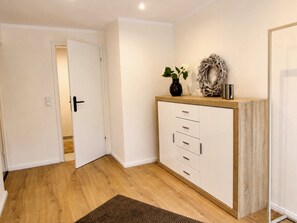 A hallway with a wooden floor, a white door, a white cabinet with drawers, and a small rug. - Herzwerk Schwalenberg by Interhome (Schwalenberg)