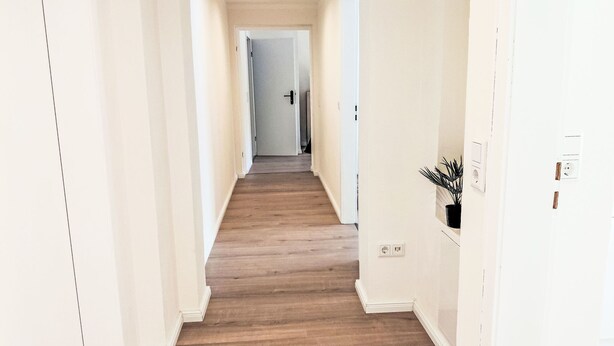 A hallway with wooden flooring, white walls, and a door at the end. - Herzwerk Schwalenberg by Interhome (Schwalenberg)