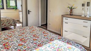 A bedroom with a floral bedspread, a wooden dresser, and a mirror. - Herzwerk Schwalenberg by Interhome (Schwalenberg)