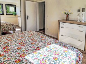 A bedroom with a floral bedspread, a wooden dresser, and a mirror. - Herzwerk Schwalenberg by Interhome (Schwalenberg)