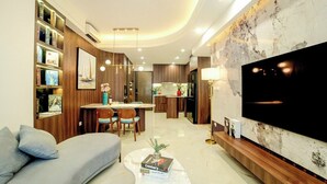 A modern living room with a sofa, coffee table, and a flat-screen TV mounted on the wall. - SOHO Vernal Saigon Apartments (Ho Chi Minh City)