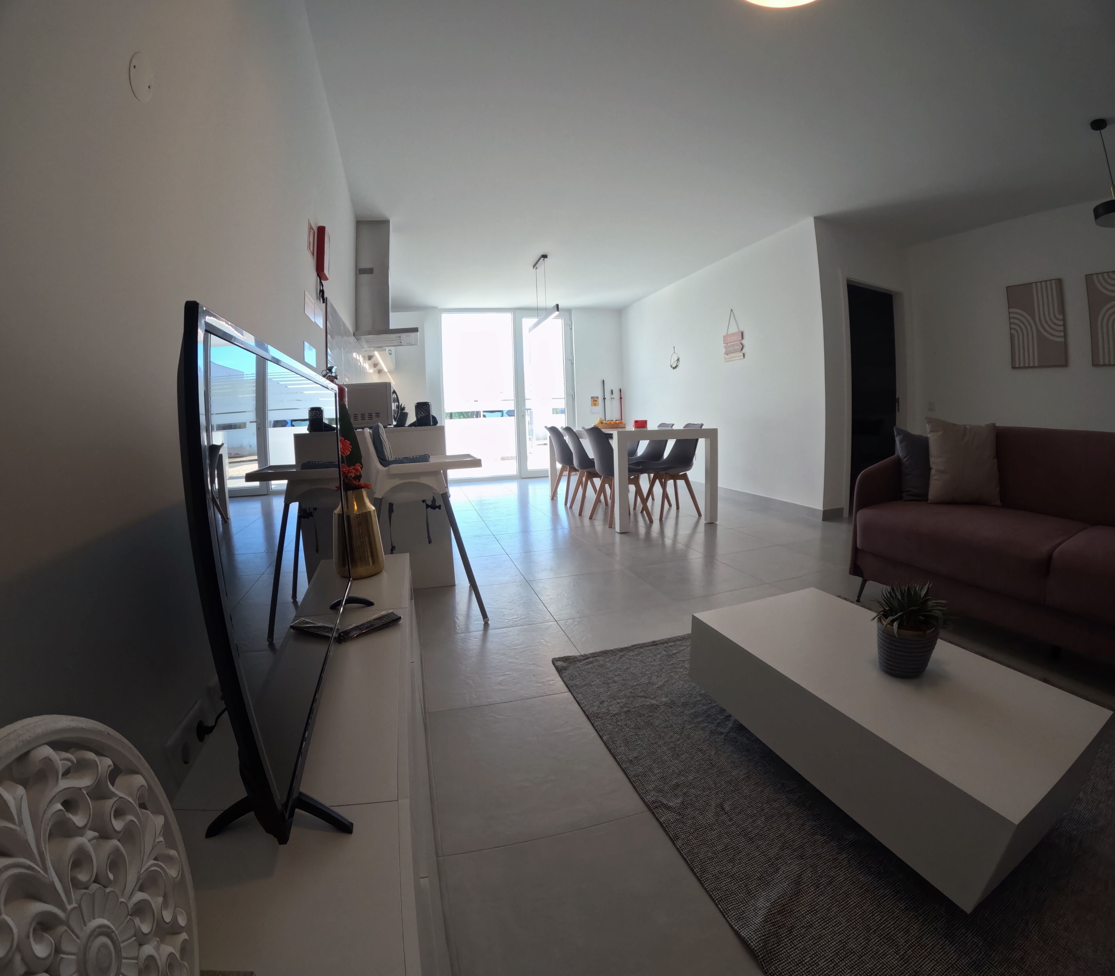 Un salon moderne avec un canapé blanc, une table basse et un coin repas comprenant une table et des chaises.