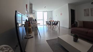 Un salon moderne avec un canapé blanc, une table basse et un coin repas comprenant une table et des chaises.