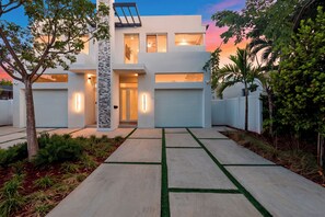 Ein modernes, zweistöckiges Haus mit Garage, einer Fassade aus Naturstein und einem gepflegten Vorgarten mit Betonweg.