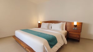 A neatly made bed with a wooden headboard and two bedside tables with lamps. - Villa Harmony (Badung)