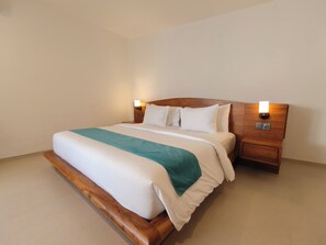 A neatly made bed with a wooden headboard and two bedside tables with lamps. - Villa Harmony (Badung)