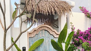A rustic wooden door with intricate carvings, a thatched roof, and lush greenery surrounding the entrance. - Villa Harmony (Badung)