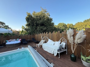 A wooden deck with a hot tub, lounge chairs, and a white canopy.