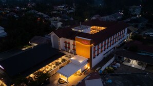 Un hotel con un letrero llamativo, un área al aire libre techada y un estacionamiento.