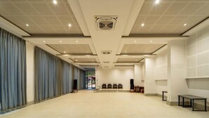 A spacious hotel lobby with a high ceiling, recessed lighting, and a central air conditioning unit.