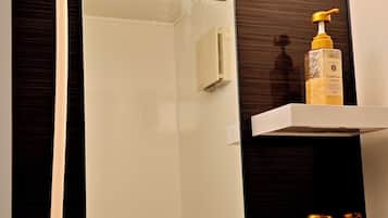 A bathroom with a shower, a mirror, and shelves with toiletries.
