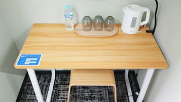 A wooden table with a water bottle, four glasses, and a kettle.