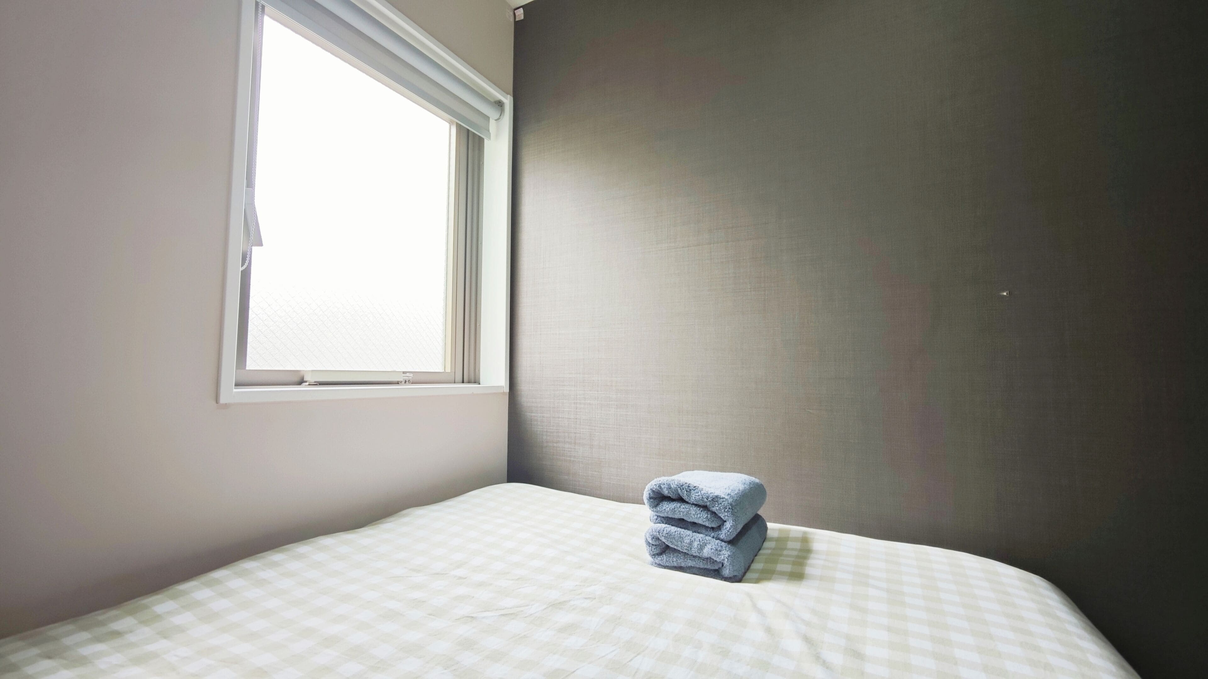 A room with a bed, a window, and a wall.