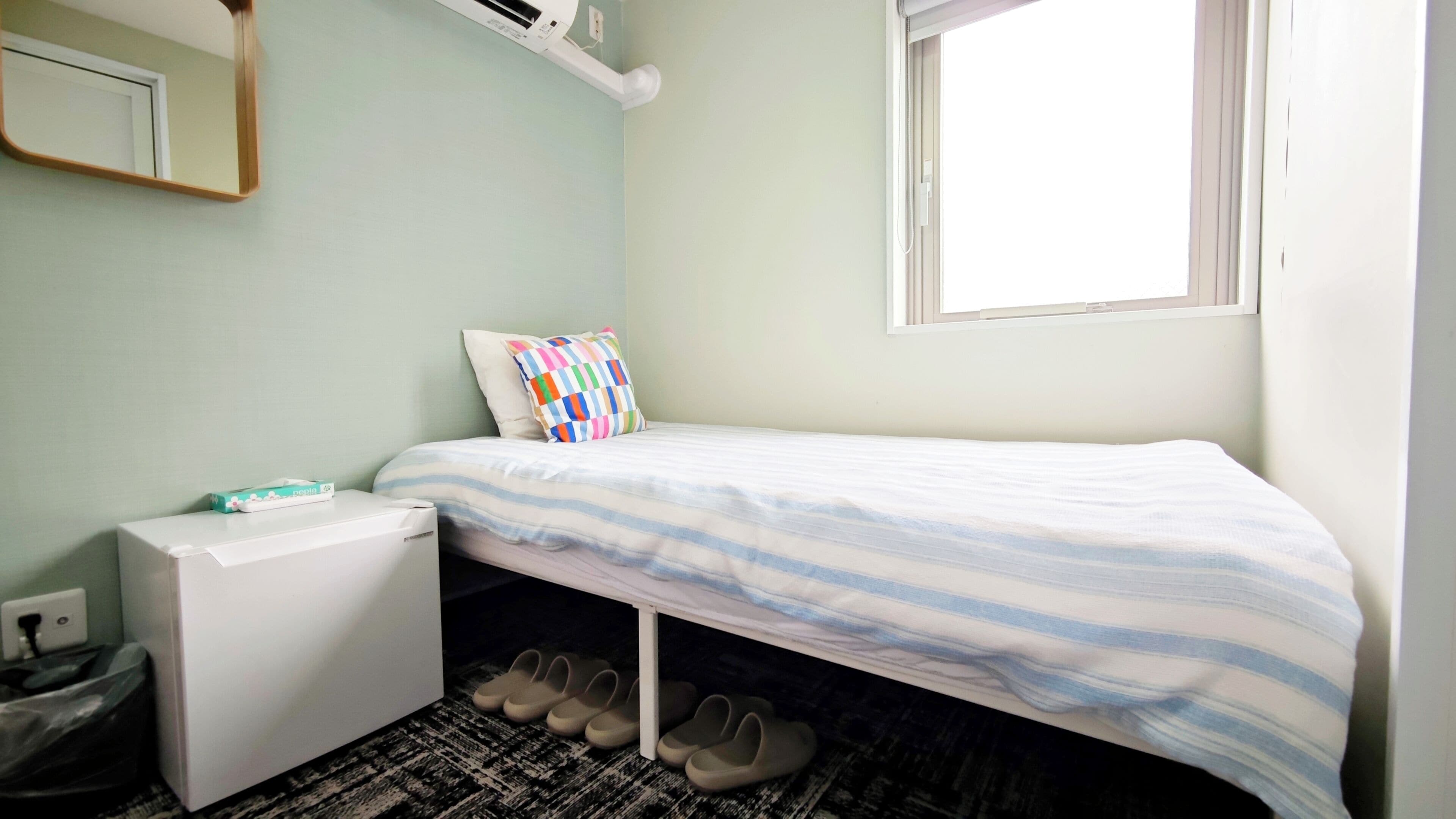 Une petite chambre à coucher, bien rangée, avec un lit, un bureau et une fenêtre.