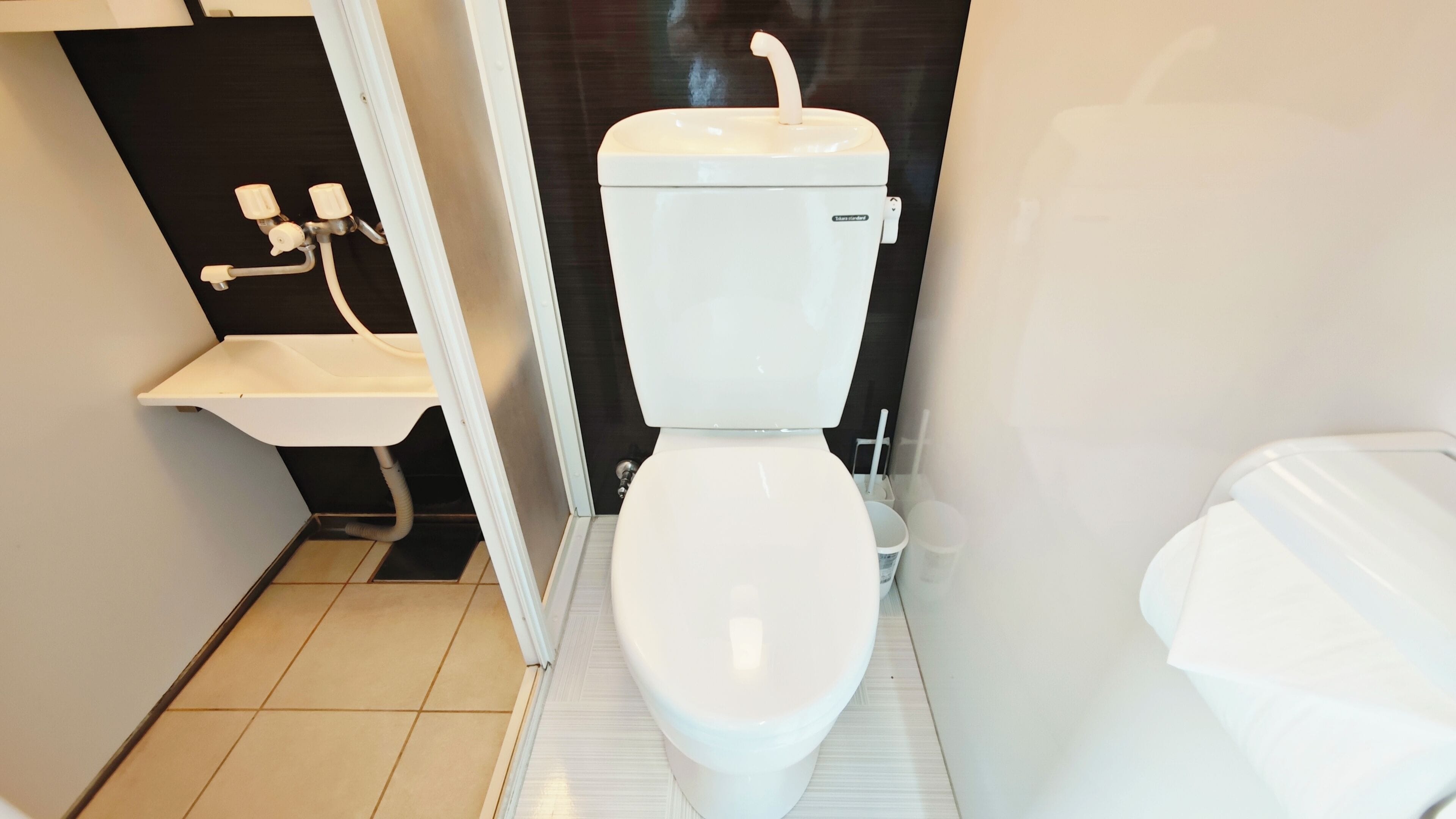 Et moderne badeværelse med toilet, håndvask og bruseniche.