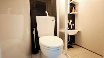 A modern bathroom with a white toilet, a black floor, and a white sink with a mirror above it.