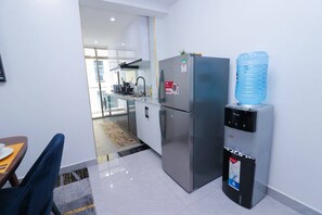 A modern kitchen with stainless steel appliances, a water dispenser, and a dining area with a table and chairs. - Goldpark Homes View Palace Apartment (Nairobi)