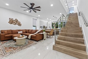 A modern living room with a brown sectional sofa, a coffee table, and a ceiling fan. - Shared Pool + BBQ + Private Balcony | Walk to Las Olas | Palm Perch (Fort Lauderdale)
