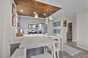 A modern kitchen with a central island, stainless steel appliances, and pendant lighting. - Royal Kuhio #1312 City Views (Honolulu)