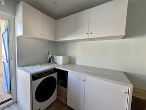 A compact kitchen with a built-in washer and dryer, white cabinetry, and a small countertop. - Large family home - Downtown Pérols (PEROLS)