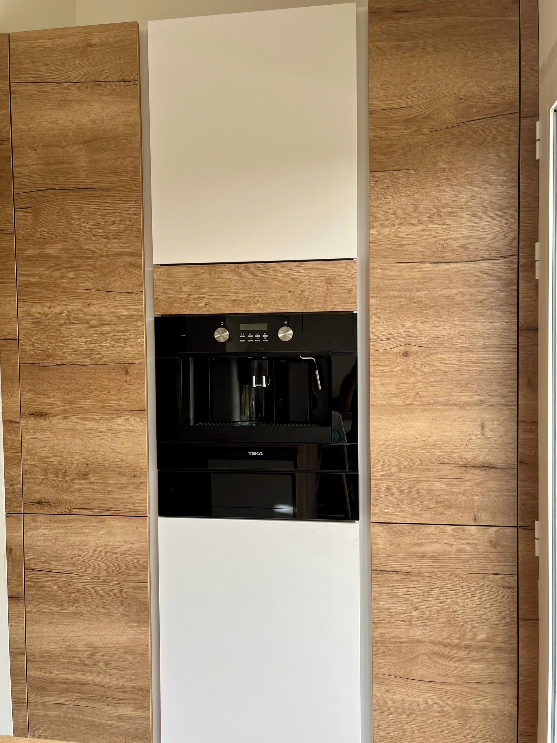 A kitchen with a built-in espresso machine and a white cabinet.