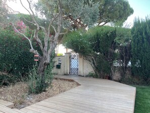 A wooden deck leading to a gated entrance with a stone wall and a metal gate. - Large family home - Downtown Pérols (PEROLS)