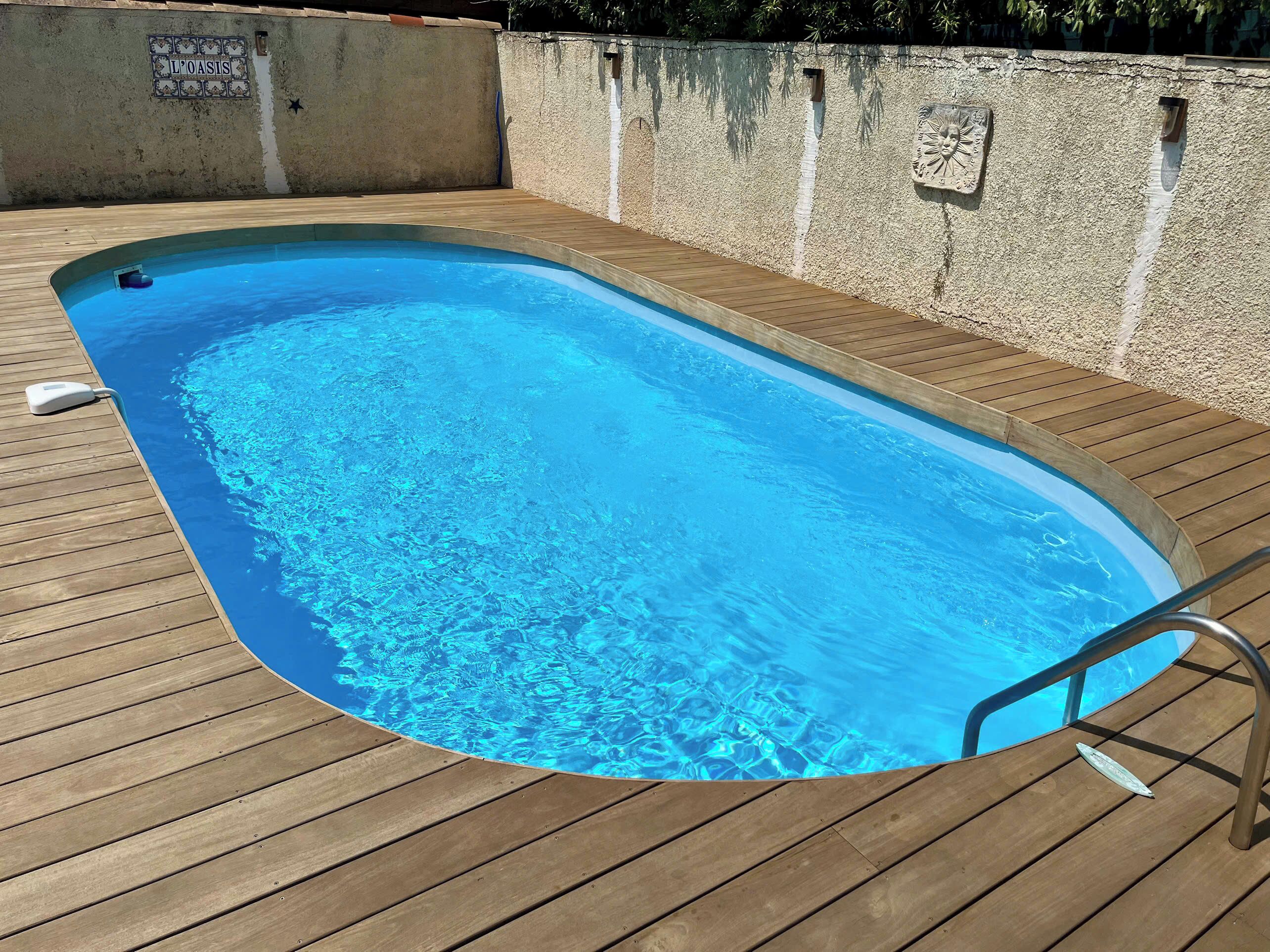 A swimming pool with a wooden deck and a metal ladder.