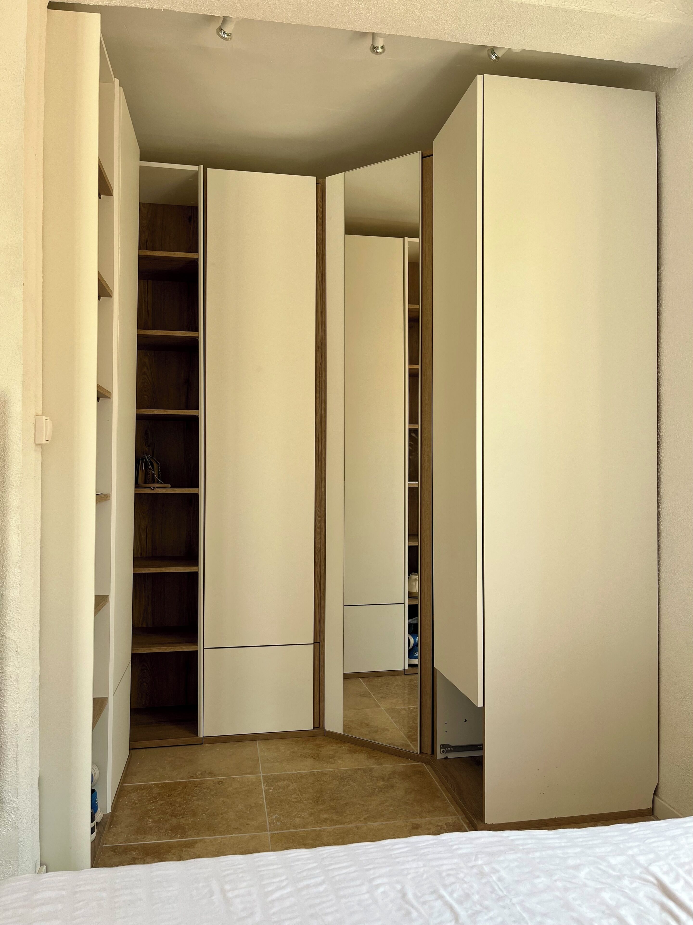 Ein Schlafzimmer mit einem Bett, einem Schrank mit Regalen und einer Tür zu einem anderen Raum.