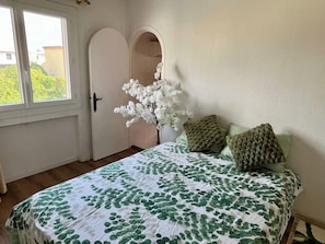 A bedroom with a bed, a window, a door, and a white wall. - Large family home - Downtown Pérols (PEROLS)