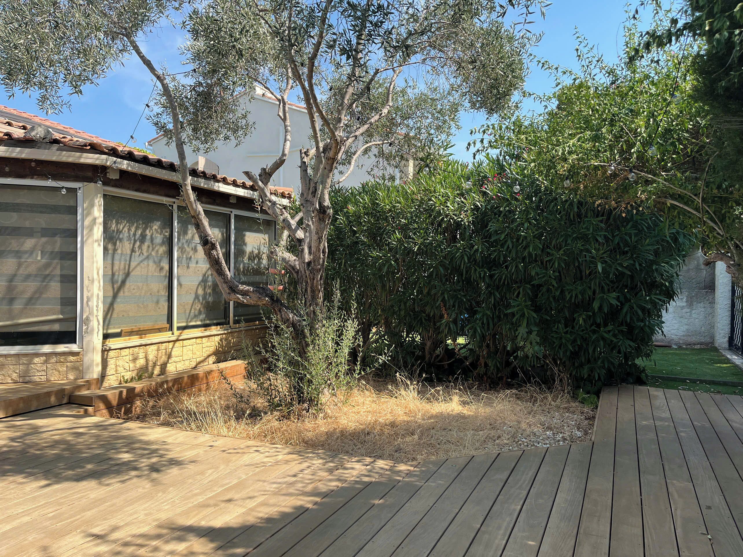 Une terrasse en bois offrant une vue sur une maison et la végétation environnante.