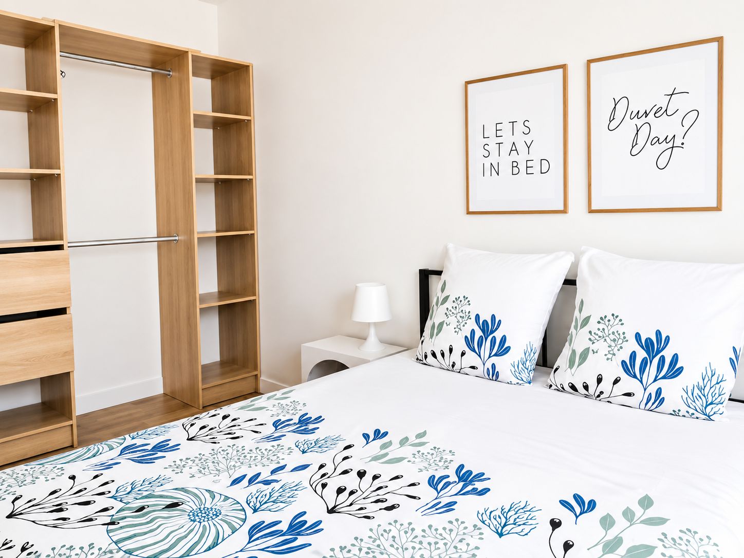 Ein Schlafzimmer mit einem Bett, einem Kleiderschrank, einem Nachttisch und zwei gerahmten Motivationspostern an der Wand.