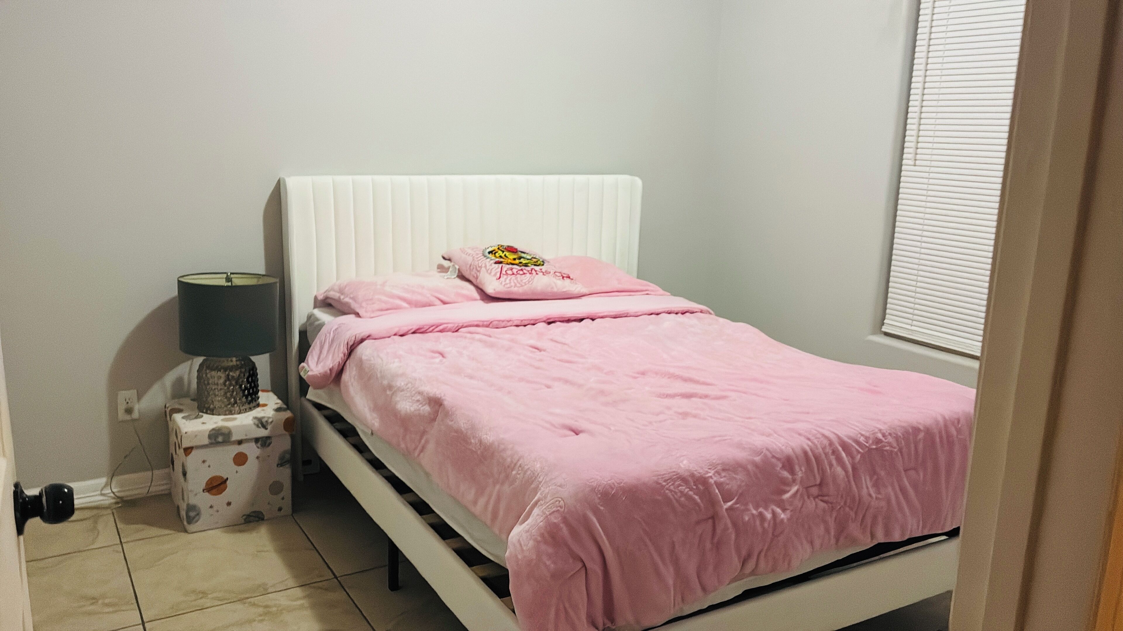 A bedroom with a bed, a bedside lamp, and a nightstand.