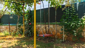 A garden with a swing set, stone wall, and climbing plants. - Casa Mandulera by Villas Guide (Vodnjan)