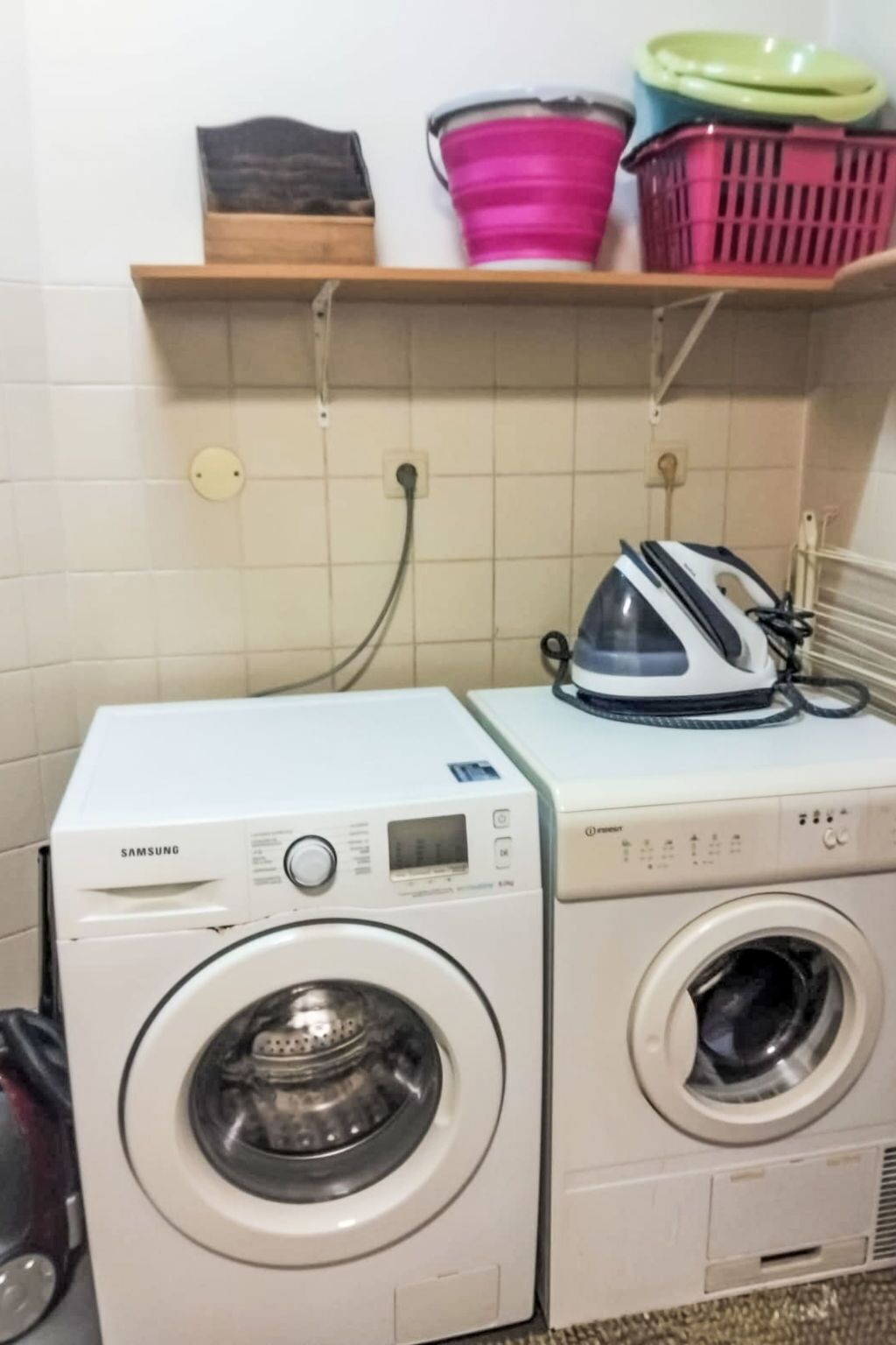Un espace buanderie équipé de deux machines à laver, d’un sèche-linge et d’un étendoir avec des paniers.