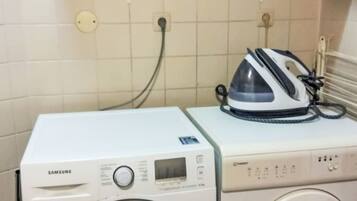 Un espace buanderie équipé de deux machines à laver, d’un sèche-linge et d’un étendoir avec des paniers.
