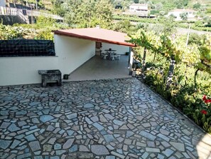A patio with a mosaic floor, a small seating area, and a view of a vineyard. - Walnut House with Private Pool by Interhome (Gondufe)
