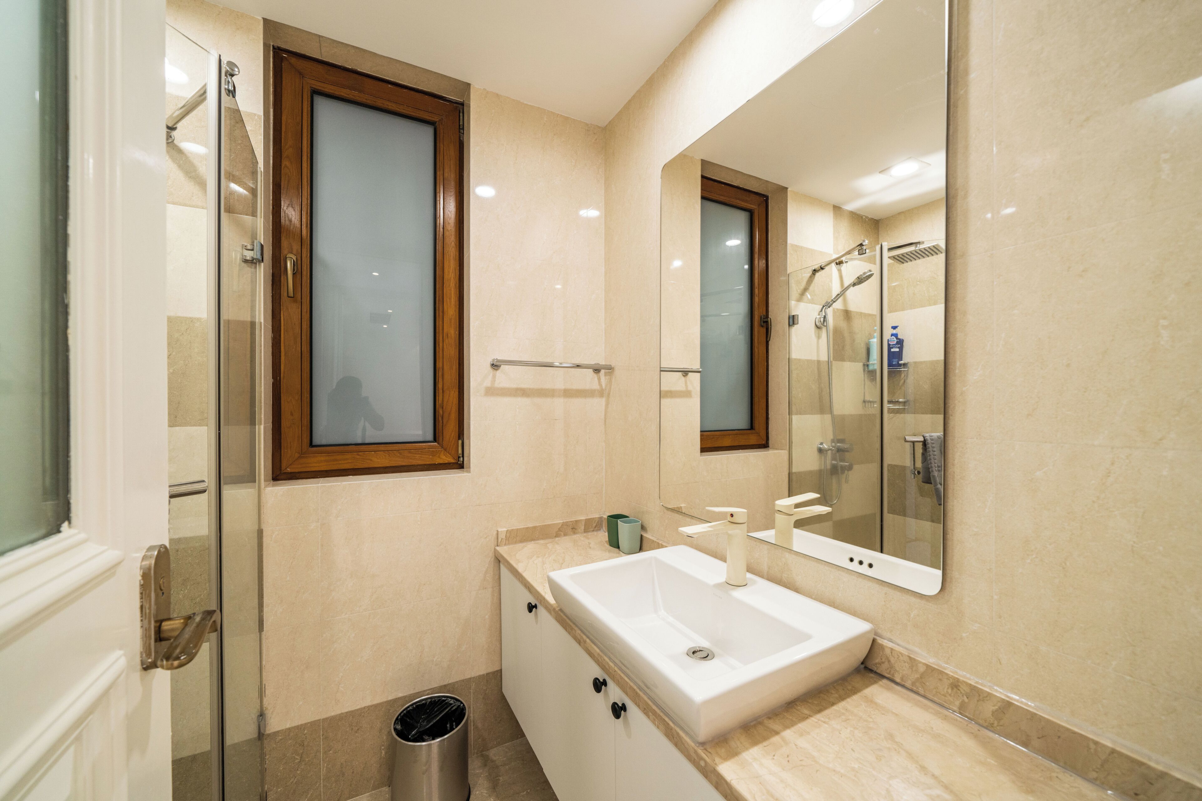 A bathroom with a glass shower enclosure, a white sink, and a mirror above the sink.