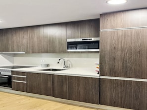 Eine moderne Küche mit dunklen Holzschränken, Edelstahlgeräten und einer weißen Arbeitsplatte.